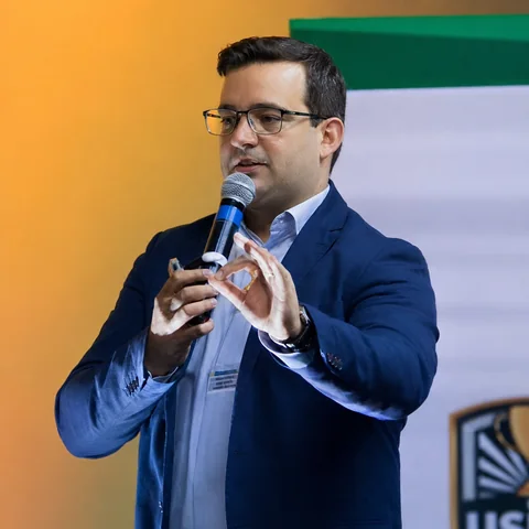Márcio Borba conduzindo palestra com microfone em evento corporativo